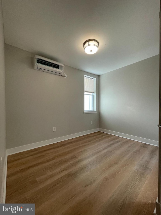 empty room with a wall mounted air conditioner and hardwood / wood-style floors