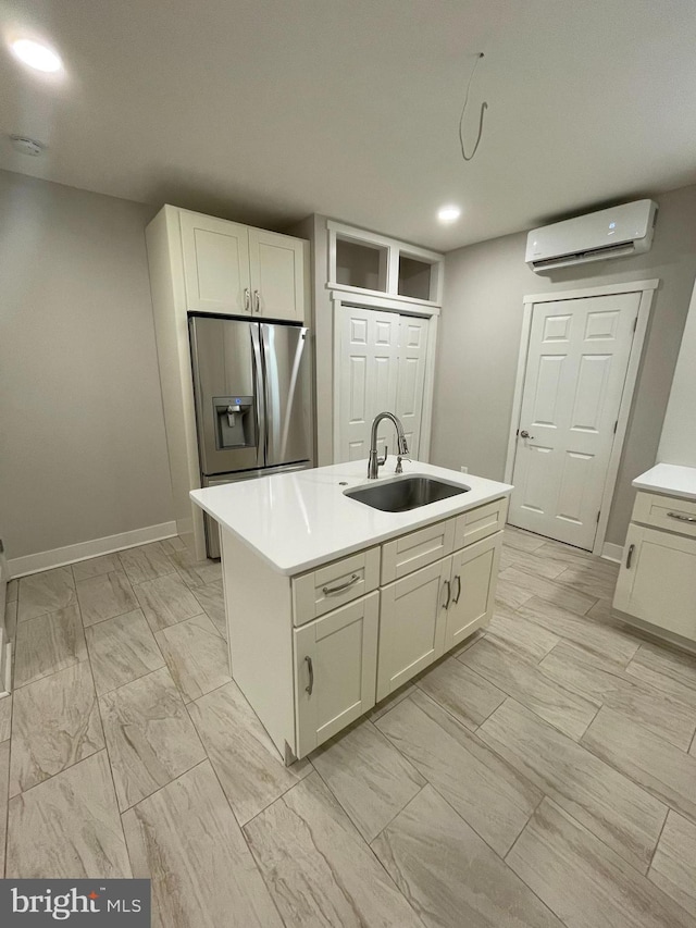 kitchen with a kitchen island with sink, sink, a wall mounted air conditioner, and stainless steel fridge