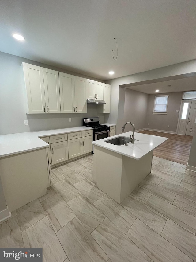 kitchen with sink, stainless steel range with gas cooktop, a center island, and white cabinets