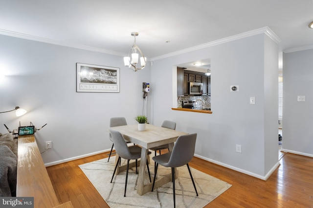 dining area featuring crown molding, an inviting chandelier, wood finished floors, and baseboards