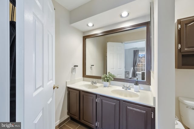 bathroom with double vanity, a sink, toilet, and recessed lighting