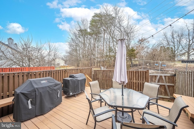 wooden deck with outdoor dining area and a grill