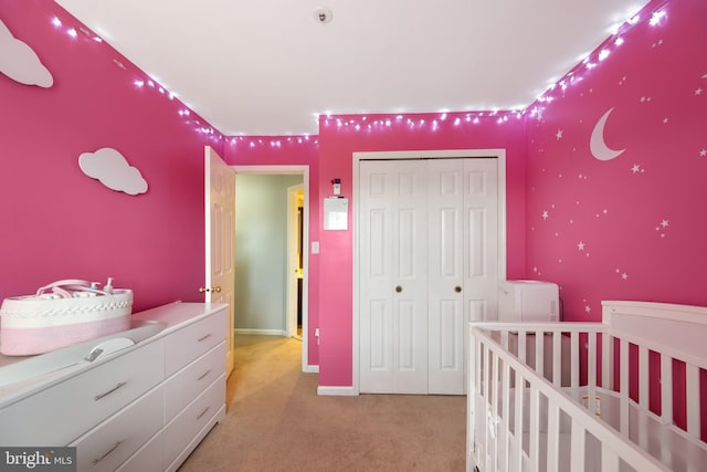 bedroom with a closet, light carpet, and baseboards