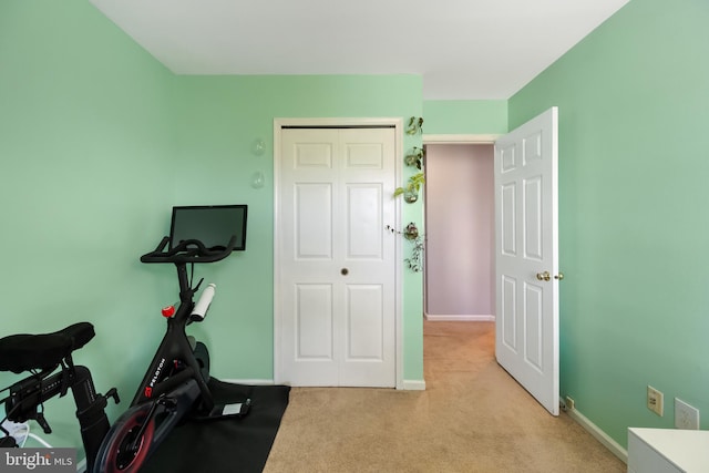 exercise room with baseboards and light colored carpet