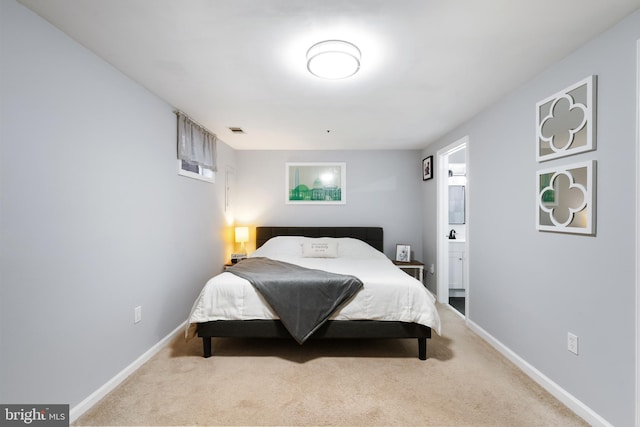 carpeted bedroom with ensuite bath, visible vents, and baseboards