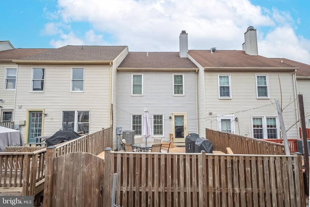 rear view of property featuring roof with shingles and fence