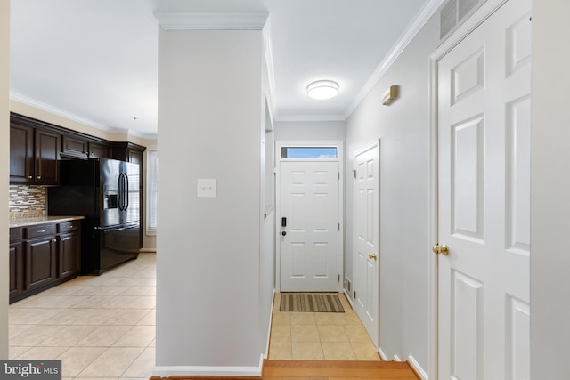 interior space featuring crown molding, visible vents, black refrigerator with ice dispenser, light tile patterned flooring, and dark brown cabinetry