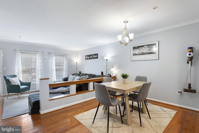 dining space with a chandelier, wood-type flooring, crown molding, and baseboards