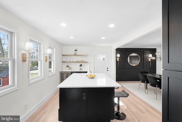 kitchen featuring light stone countertops, a breakfast bar area, light hardwood / wood-style floors, and a center island