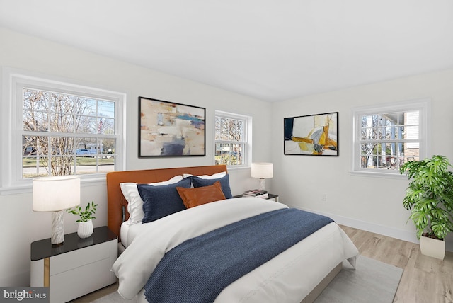 bedroom with multiple windows and light hardwood / wood-style flooring