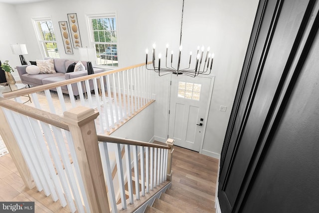 stairs featuring wood-type flooring and a chandelier