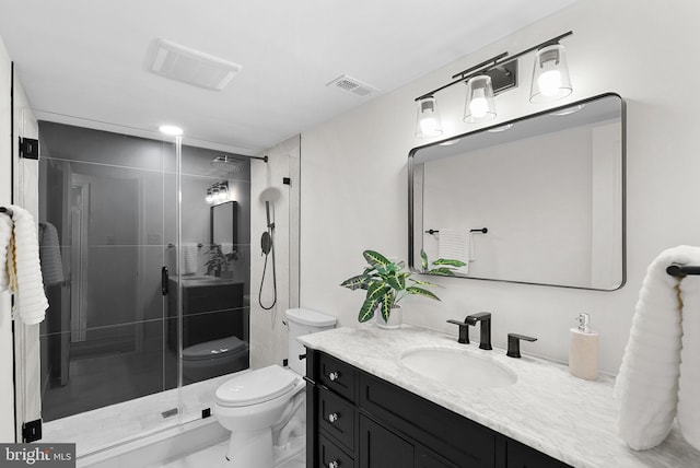 bathroom with vanity, a shower with shower door, and toilet