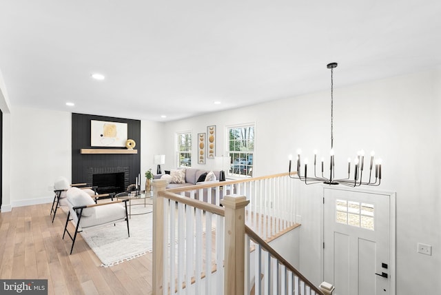 living room with a brick fireplace, light hardwood / wood-style floors, and a chandelier