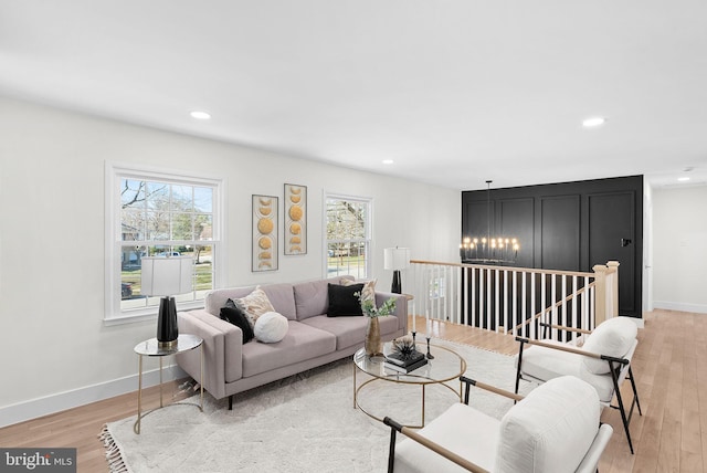 living room with a wealth of natural light, a notable chandelier, and light hardwood / wood-style floors