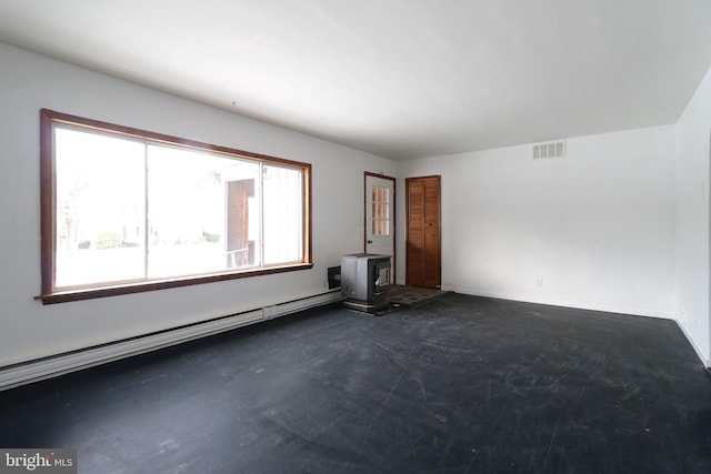 unfurnished room with baseboard heating and a wood stove