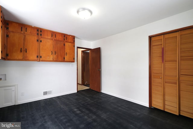 unfurnished bedroom with dark hardwood / wood-style flooring and a closet