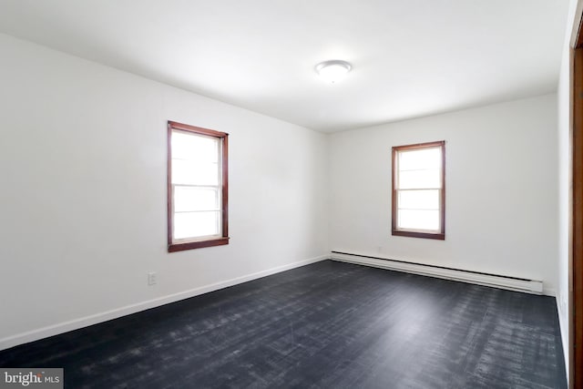 unfurnished room with dark hardwood / wood-style flooring and a baseboard heating unit