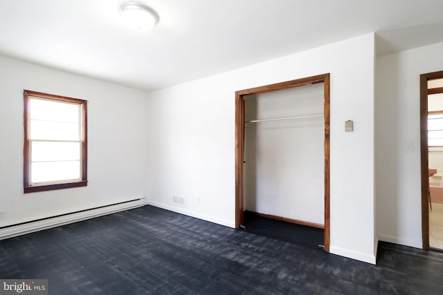 unfurnished bedroom with multiple windows, dark hardwood / wood-style flooring, and baseboard heating