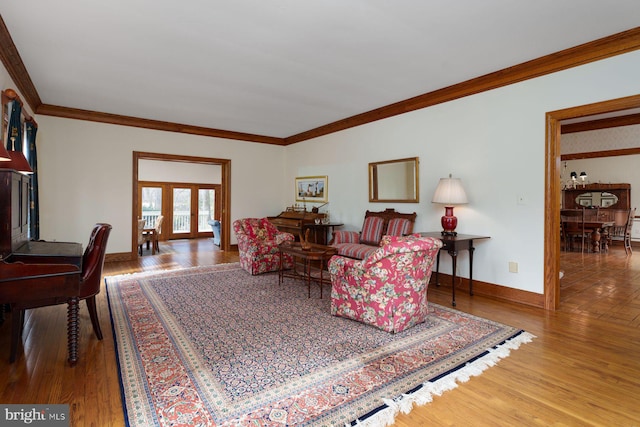 living room with wood finished floors, french doors, baseboards, and ornamental molding