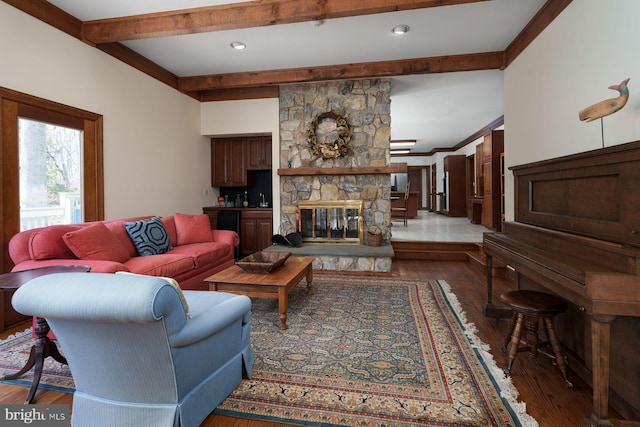 living area featuring a fireplace, beamed ceiling, wood finished floors, and ornamental molding