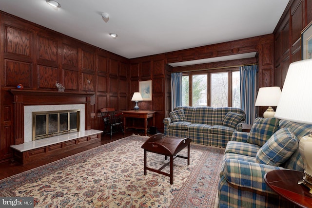 living room featuring wood finished floors, wooden walls, and a fireplace