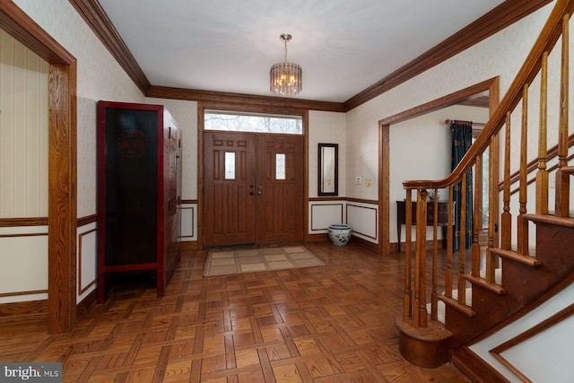 entryway with a notable chandelier, wallpapered walls, crown molding, and baseboards