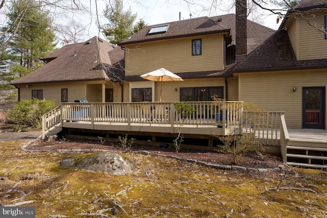 back of property featuring roof with shingles and a wooden deck