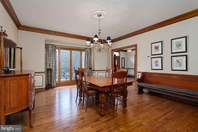 dining area with a notable chandelier, crown molding, and hardwood / wood-style floors