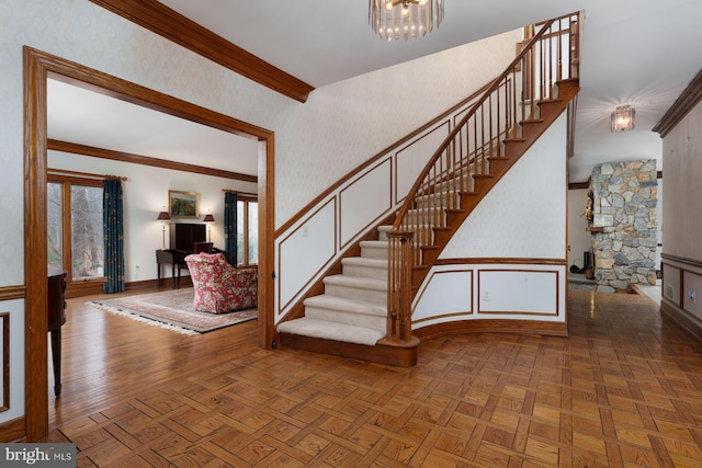 staircase with an inviting chandelier, parquet flooring, baseboards, and ornamental molding