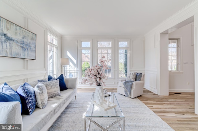 living room with ornamental molding, a wealth of natural light, and a decorative wall