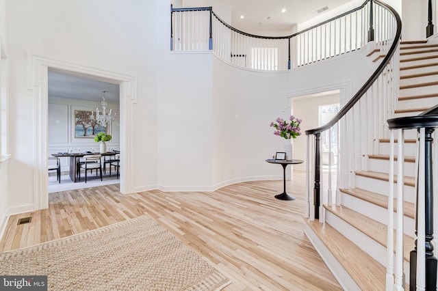 foyer featuring visible vents, a high ceiling, wood finished floors, a chandelier, and stairs