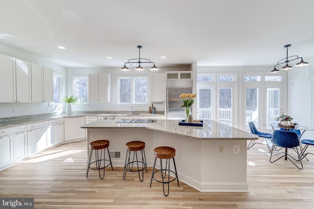 kitchen featuring hanging light fixtures, stainless steel built in fridge, and a center island