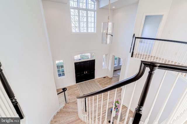 stairway featuring a towering ceiling, wood finished floors, and recessed lighting