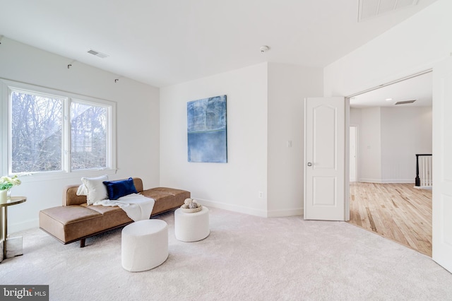 sitting room with baseboards, visible vents, and light colored carpet