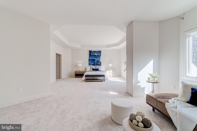 bedroom featuring light carpet, a raised ceiling, and baseboards