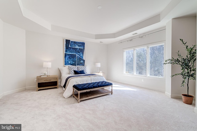 bedroom featuring light carpet, baseboards, and a raised ceiling