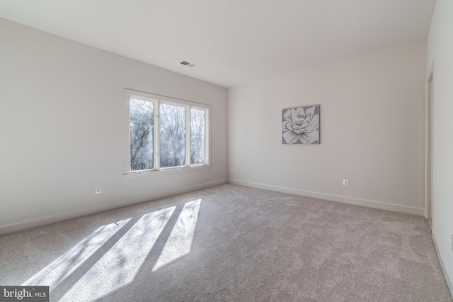 spare room with light colored carpet, visible vents, and baseboards