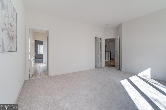 unfurnished bedroom featuring light carpet and baseboards