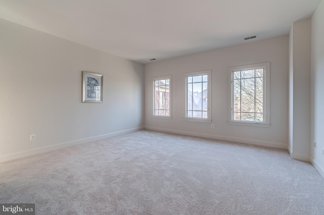 empty room featuring visible vents, light carpet, and baseboards