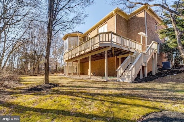 rear view of house featuring a wooden deck, stairs, a yard, central air condition unit, and brick siding