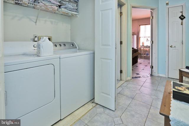 clothes washing area featuring light tile patterned floors and washing machine and dryer