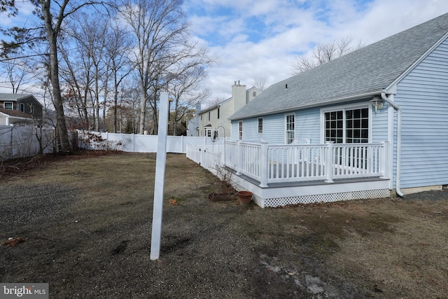 rear view of house with a wooden deck and a lawn