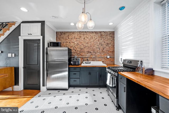 kitchen with pendant lighting, butcher block countertops, sink, stainless steel appliances, and crown molding