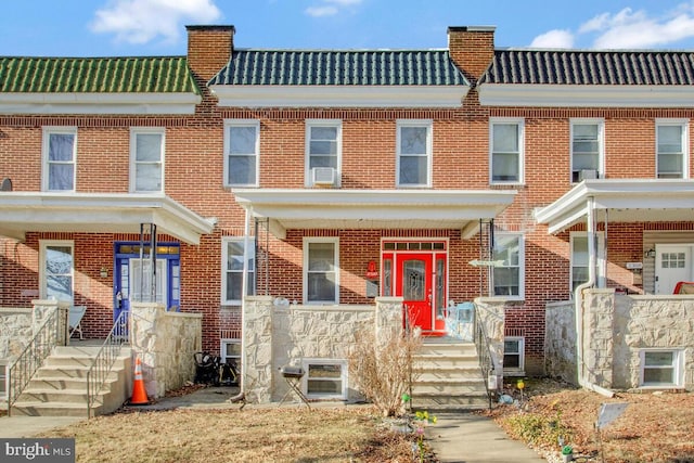 townhome / multi-family property featuring brick siding, a chimney, and a tile roof