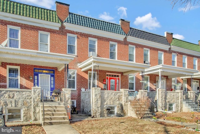 multi unit property with a chimney, brick siding, and a tiled roof