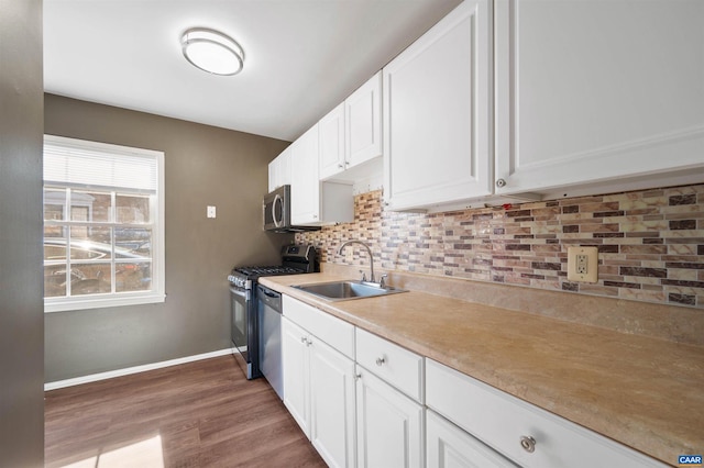 kitchen with tasteful backsplash, appliances with stainless steel finishes, sink, and white cabinets