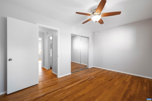 unfurnished bedroom with hardwood / wood-style floors, a closet, and ceiling fan