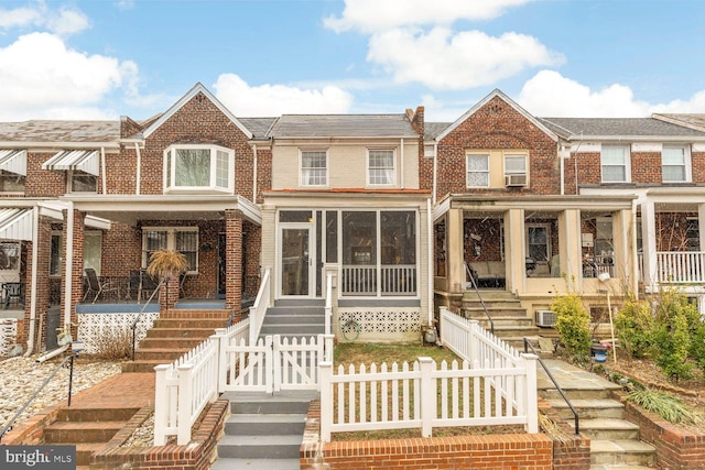 view of front facade featuring cooling unit, covered porch, brick siding, fence, and stairway