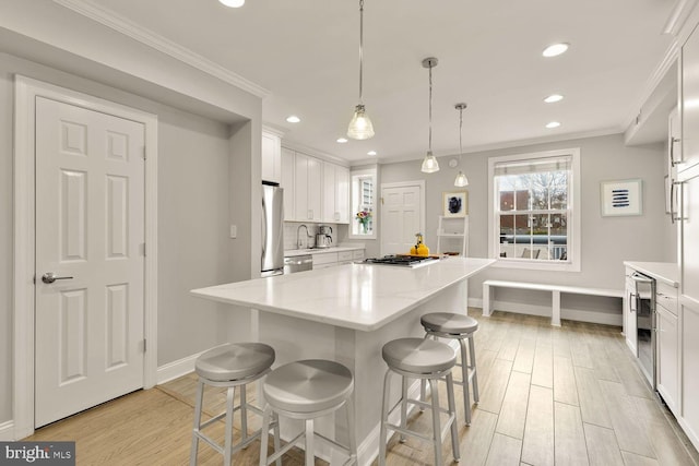 kitchen featuring crown molding, stainless steel appliances, light wood-style flooring, and white cabinetry