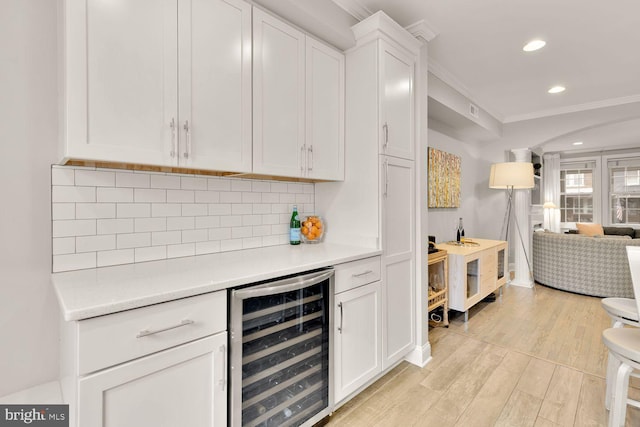 bar featuring crown molding, light wood finished floors, recessed lighting, backsplash, and beverage cooler